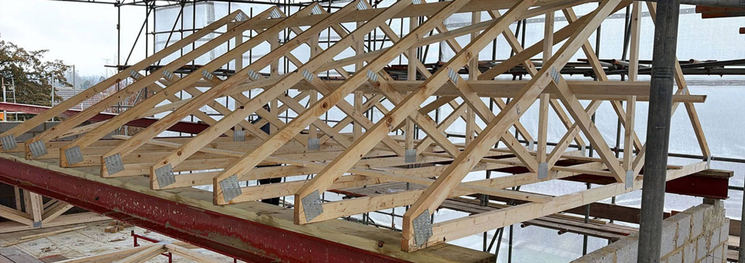 Wooden roofing trusses under construction for loft conversion with scaffolding for this property development.
