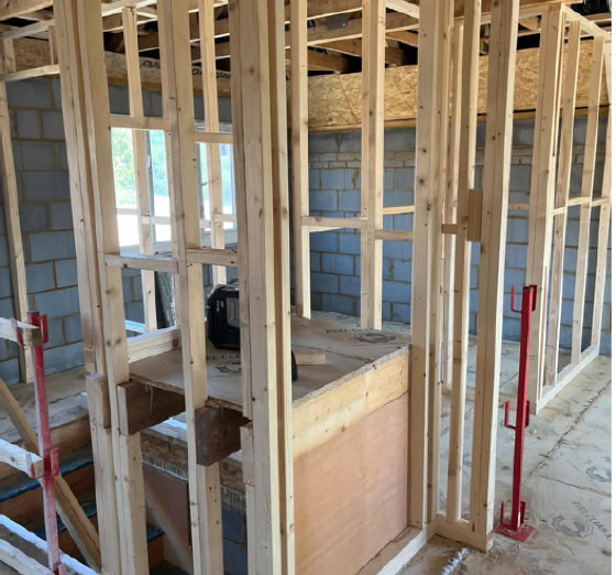 Wooden framing structure of a building under construction with exposed beams and partially completed walls.